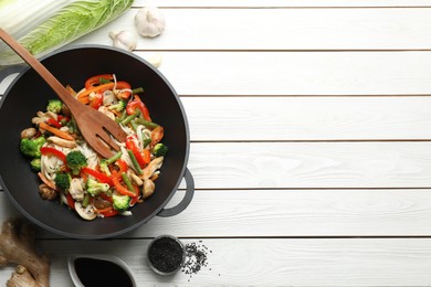 Photo of Stir fried noodles with mushrooms, chicken and vegetables in wok on white wooden table, flat lay. Space for text