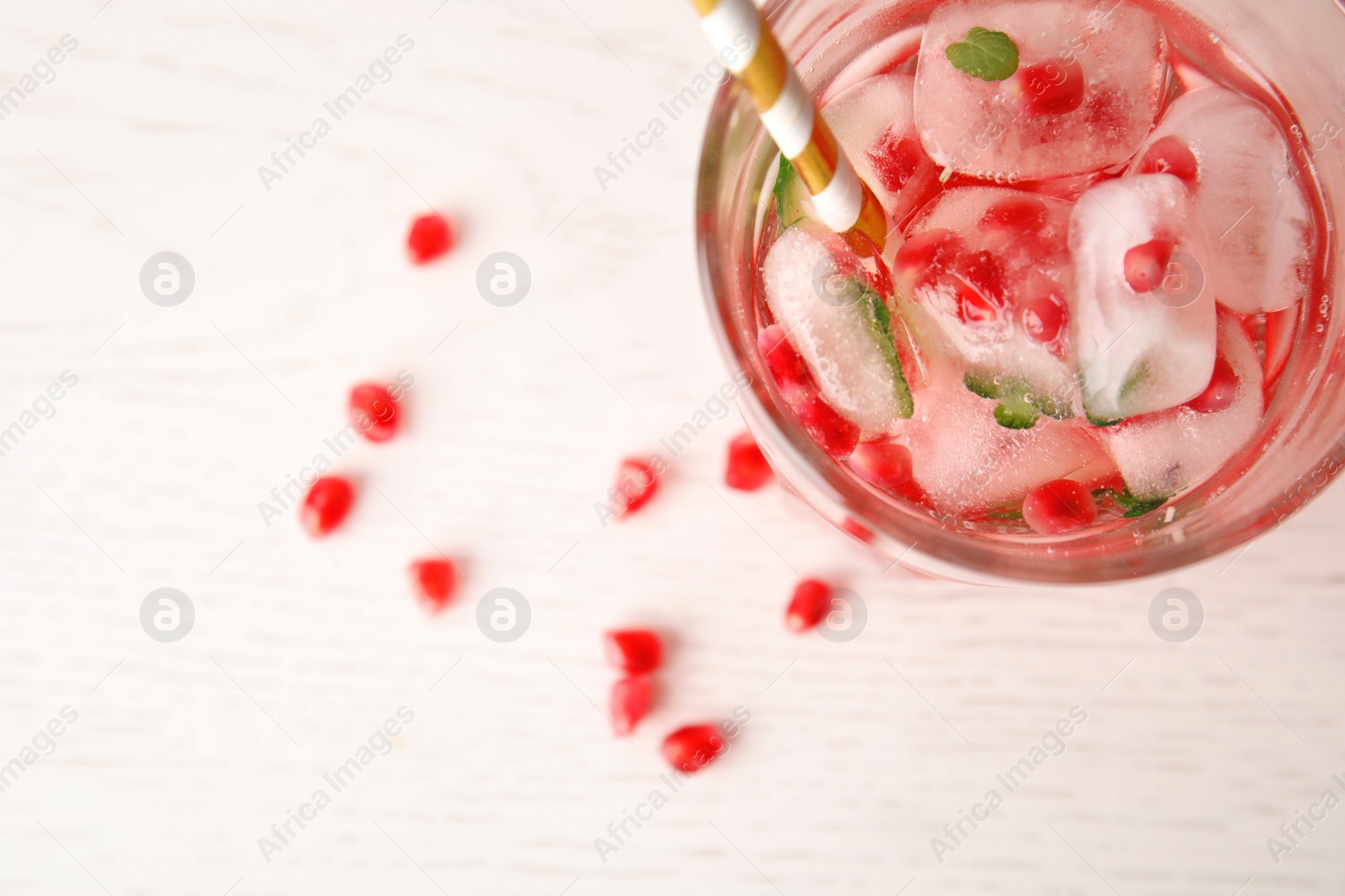 Photo of Tasty cocktail with pomegranate ice cubes and seeds on table, top view. Space for text