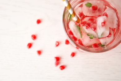 Tasty cocktail with pomegranate ice cubes and seeds on table, top view. Space for text