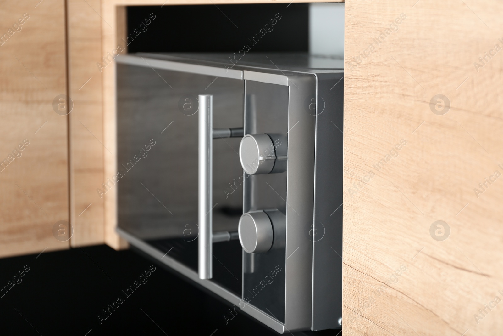 Photo of Modern microwave oven on shelf in kitchen