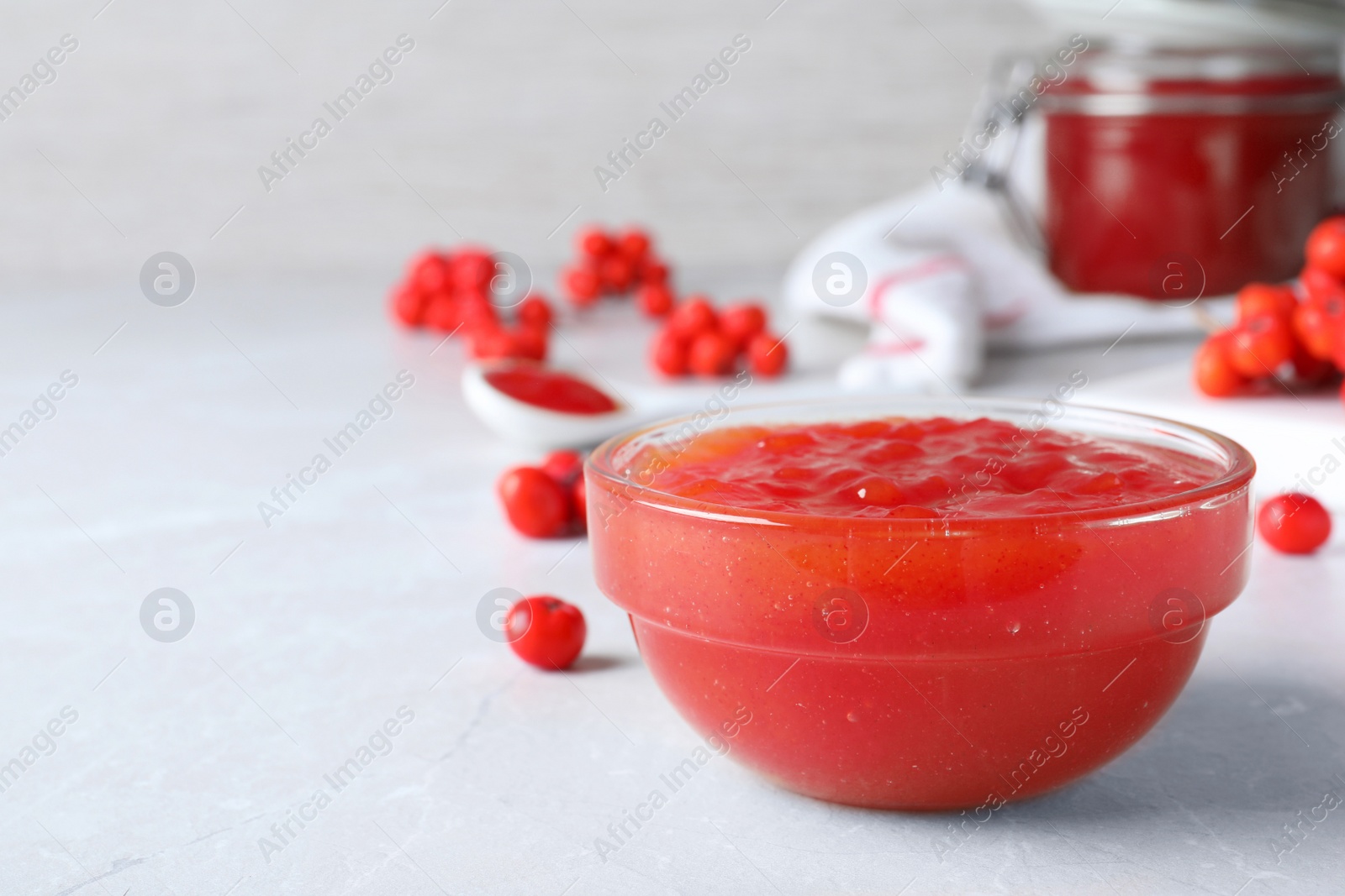 Photo of Delicious rowan jam in bowl on light table. Space for text