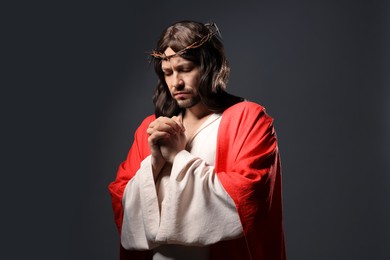 Photo of Jesus Christ with crown of thorns praying on grey background