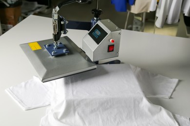 Photo of Printing logo. Heat press with t-shirt on white table