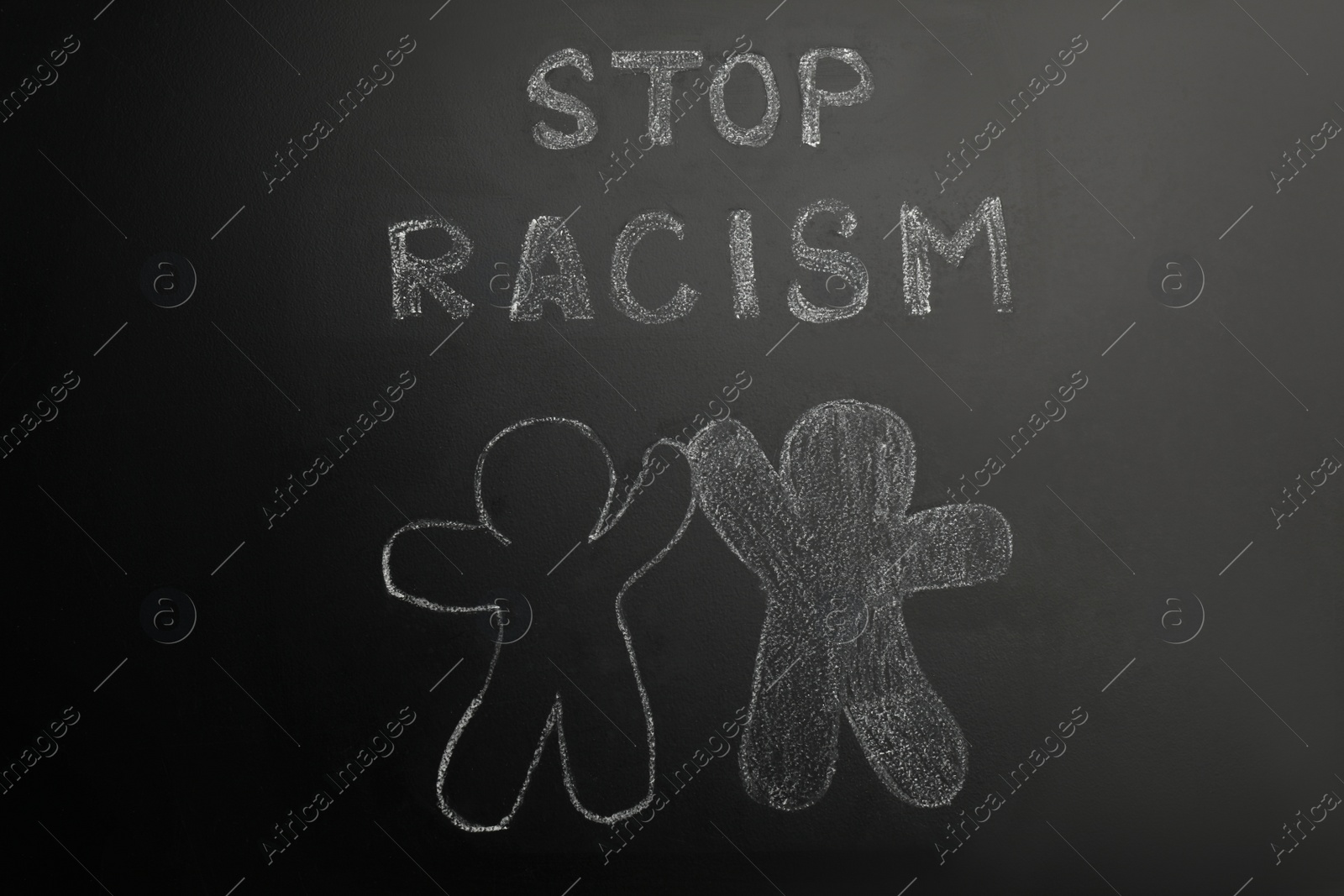 Photo of Chalked inscription Stop Racism and people figures on blackboard