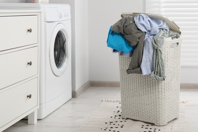 Plastic laundry basket overfilled with clothes in bathroom