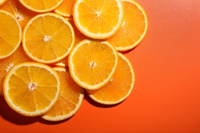 Photo of Slices of juicy orange on terracotta background, top view. Space for text