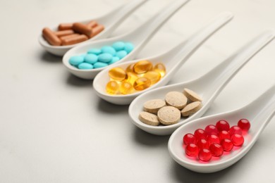 Photo of Spoons with different dietary supplements on white table. Space for text