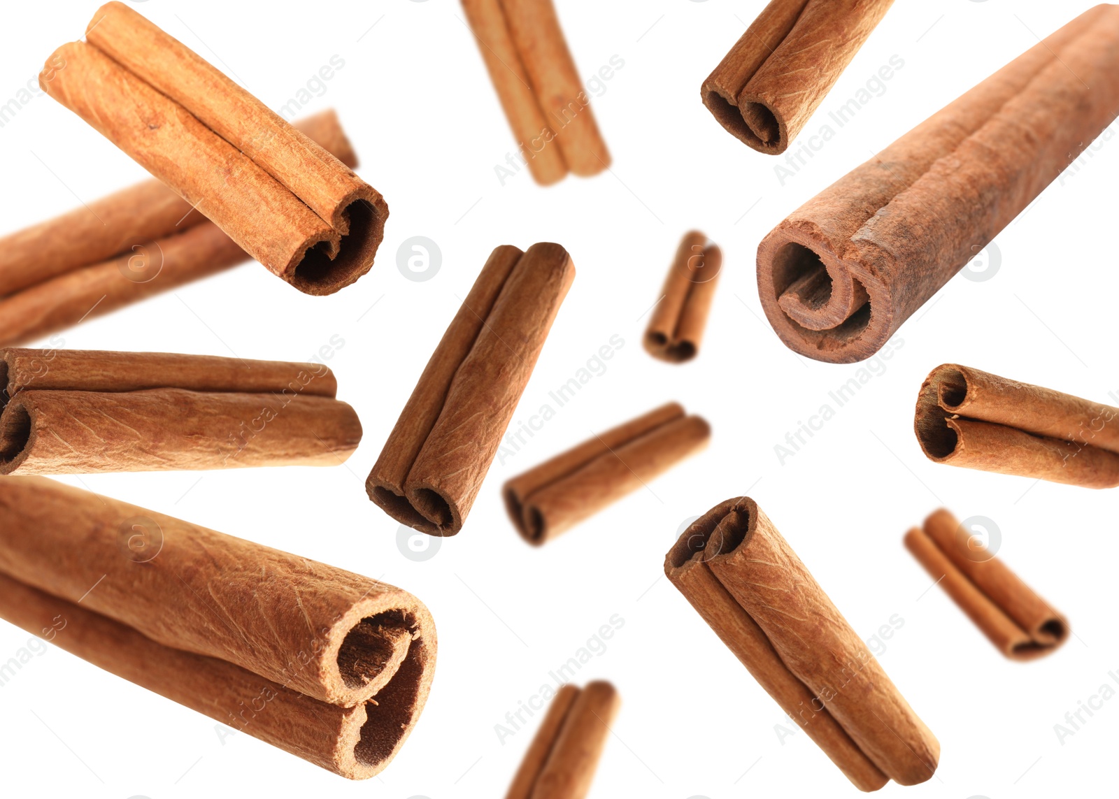 Image of Aromatic cinnamon sticks falling on white background