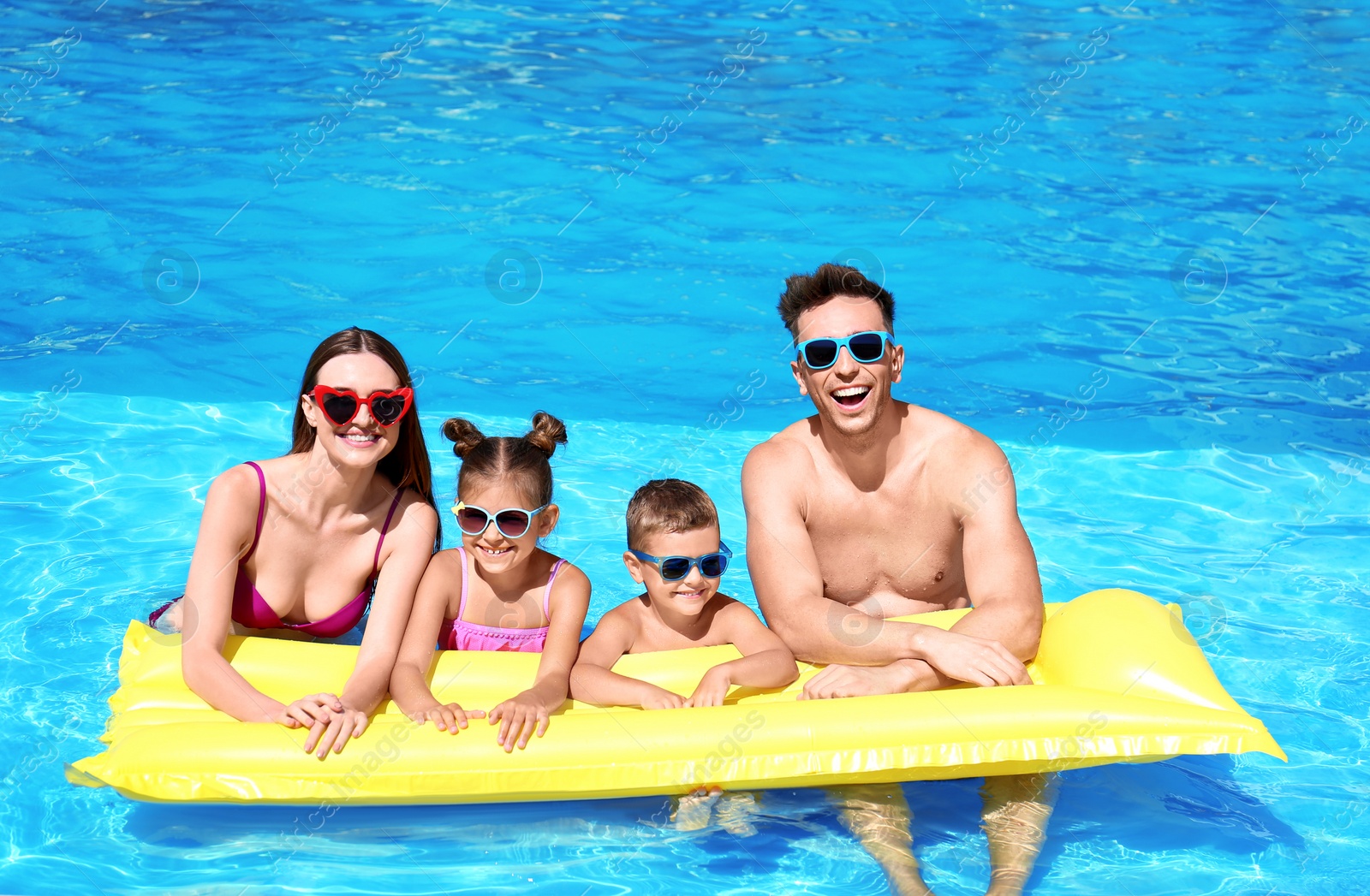 Photo of Happy family with inflatable mattress in swimming pool