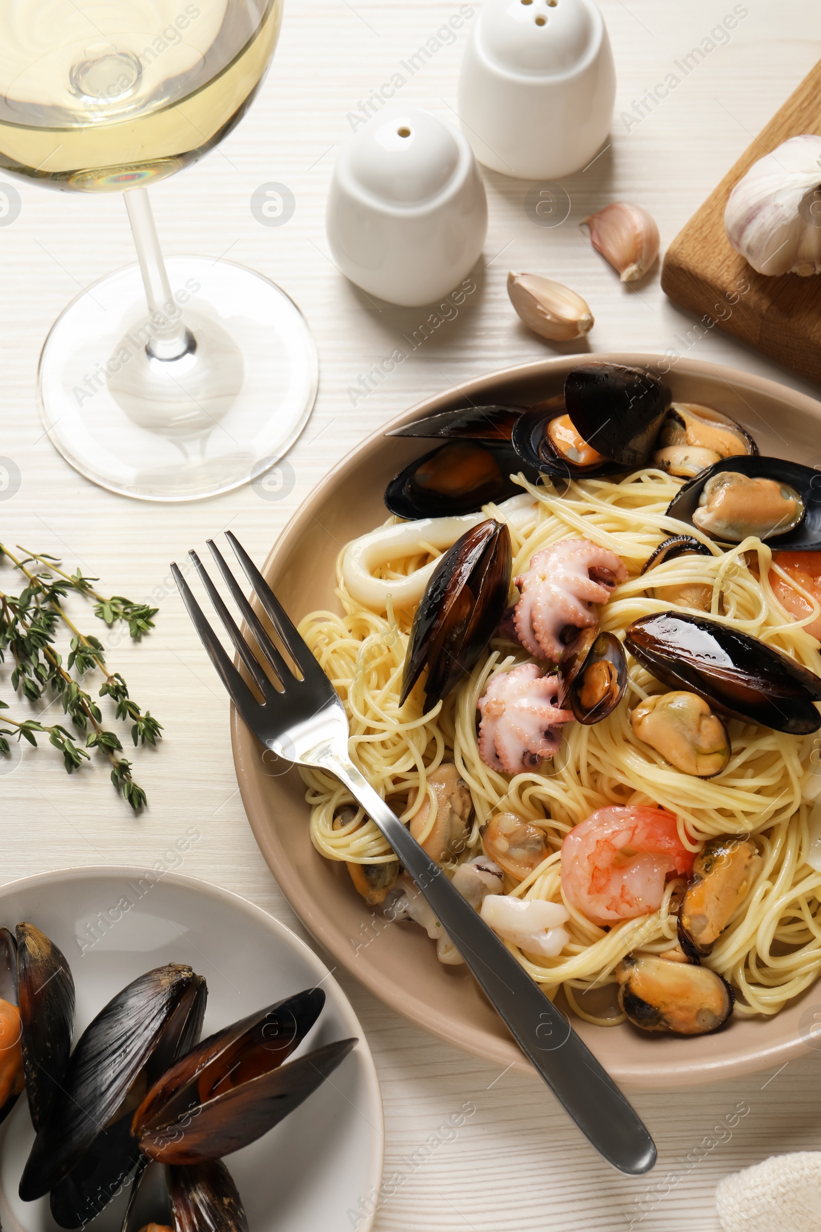 Photo of Delicious pasta with sea food served on white wooden table, flat lay