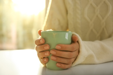 Photo of Woman holding elegant cup at table indoors, closeup
