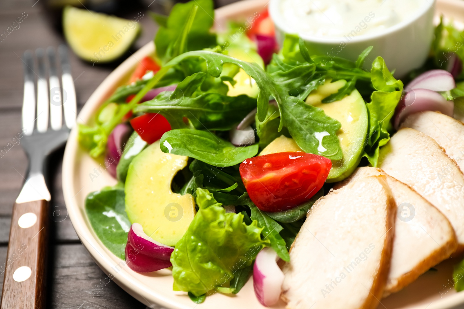Photo of Delicious salad with chicken, arugula and avocado on wooden table, closeup