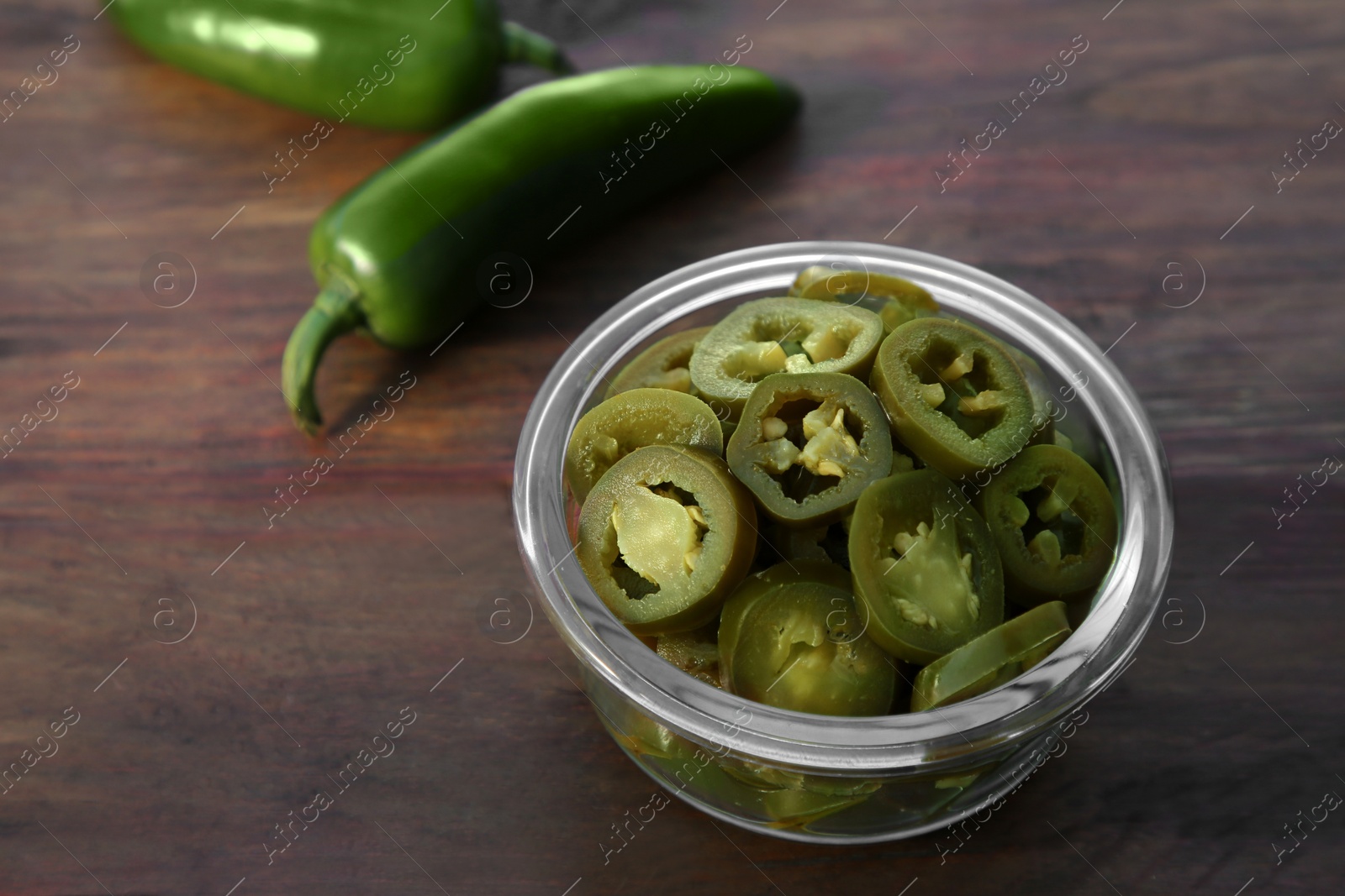 Photo of Fresh and pickled green jalapeno peppers on wooden table, closeup. Space for text