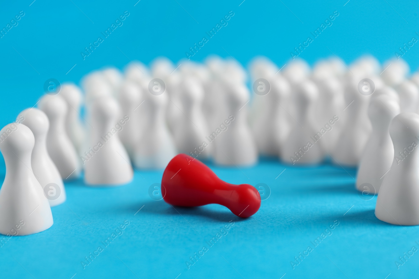 Photo of Fallen red pawn among others on light blue background, closeup. Social inclusion concept