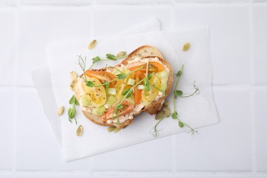 Photo of Tasty vegan sandwich with tomatoes, celery and microgreens on white tiled table, top view