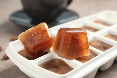 Ice cube tray with frozen coffee on table, closeup