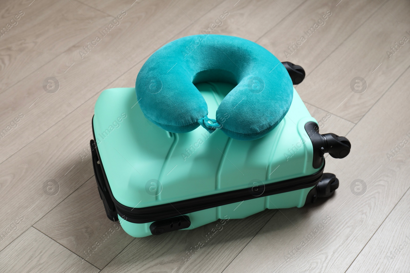 Photo of Turquoise travel pillow and suitcase on floor