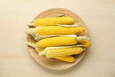 Tasty sweet corn cobs on wooden table, flat lay