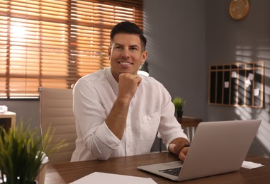 Photo of Freelancer working on laptop at table indoors