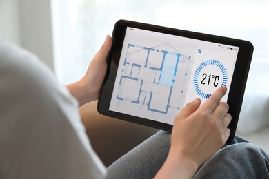 Woman using tablet to control heating system in house, closeup