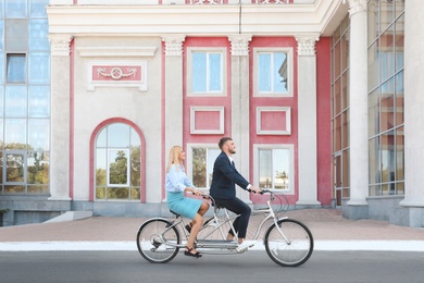 Couple riding tandem bike on city street