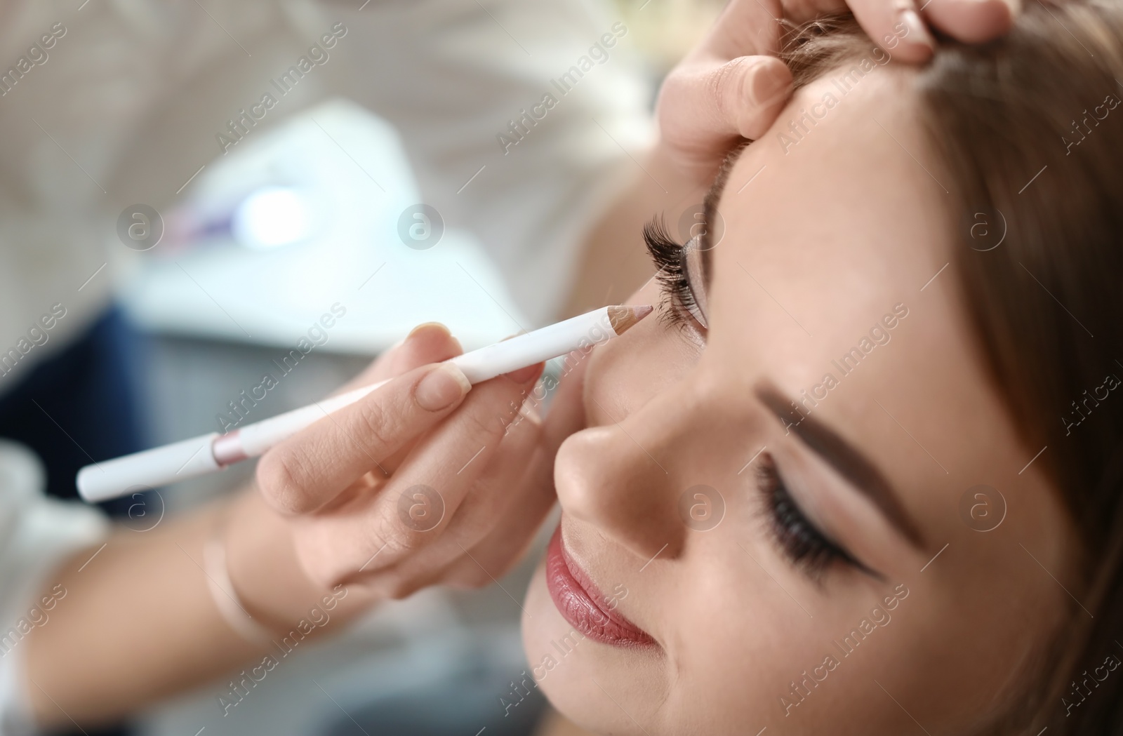 Photo of Professional makeup artist working with beautiful young woman in studio