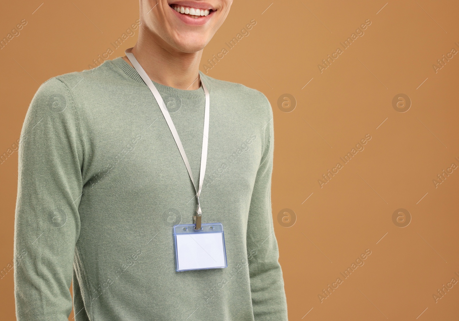 Photo of Man with blank badge on light brown background, closeup. Space for text