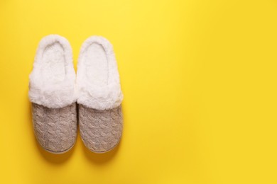 Photo of Pair of beautiful soft slippers on yellow background, top view. Space for text