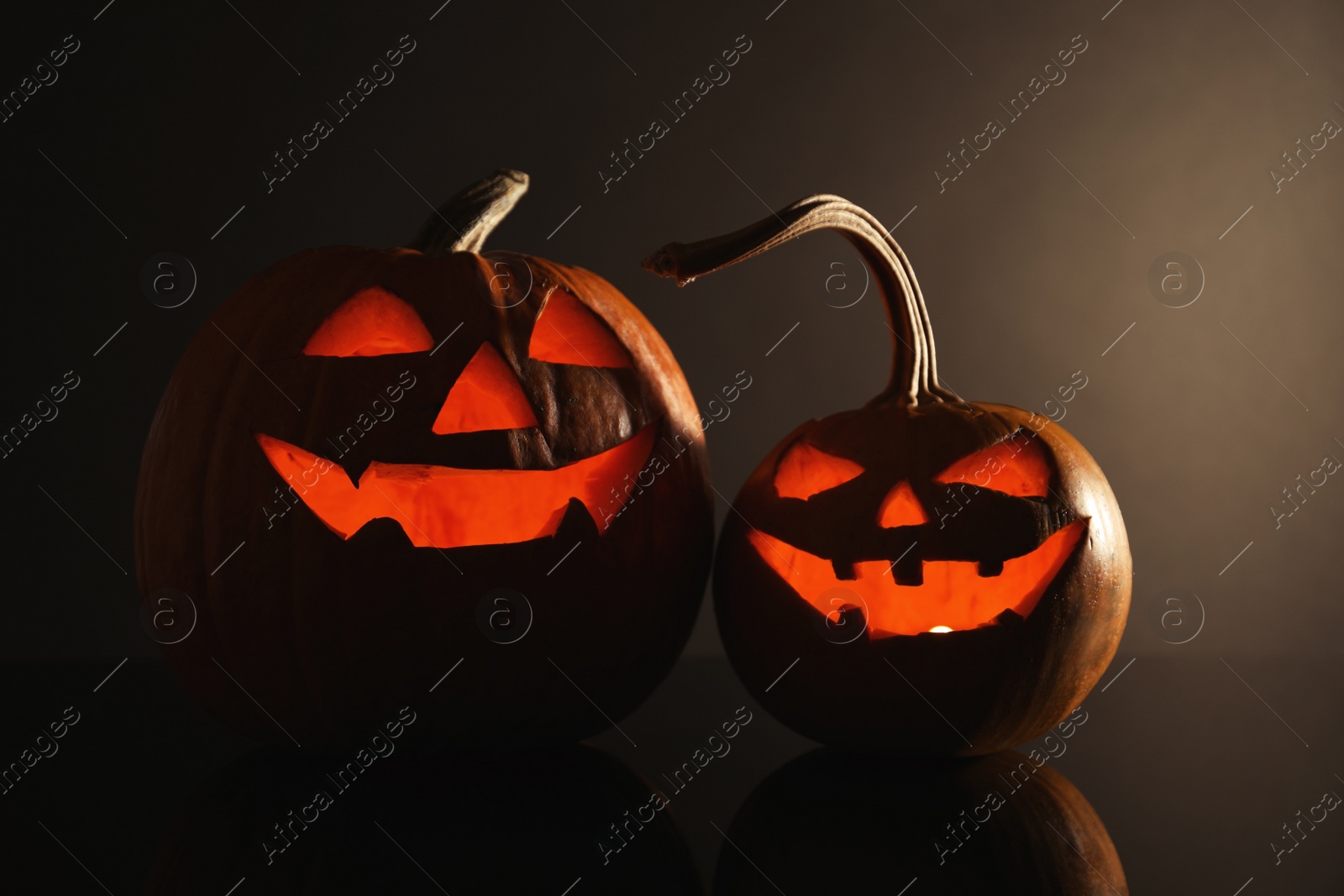 Photo of Halloween pumpkin heads. Glowing jack lanterns on dark background