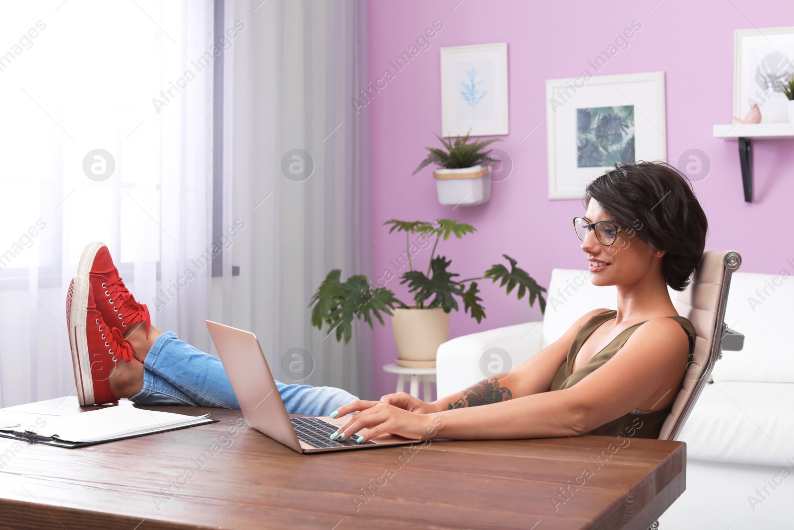 Photo of Young woman with modern laptop at desk in home office