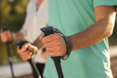 Photo of Man practicing Nordic walking with poles outdoors, closeup