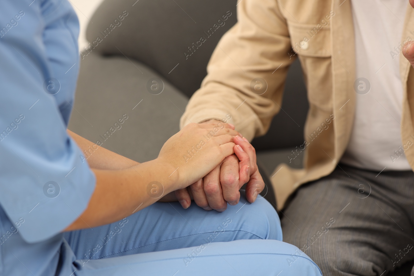 Photo of Nurse supporting elderly patient indoors, closeup view