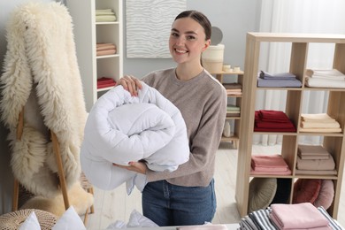 Photo of Smiling young woman with duvet in home textiles store