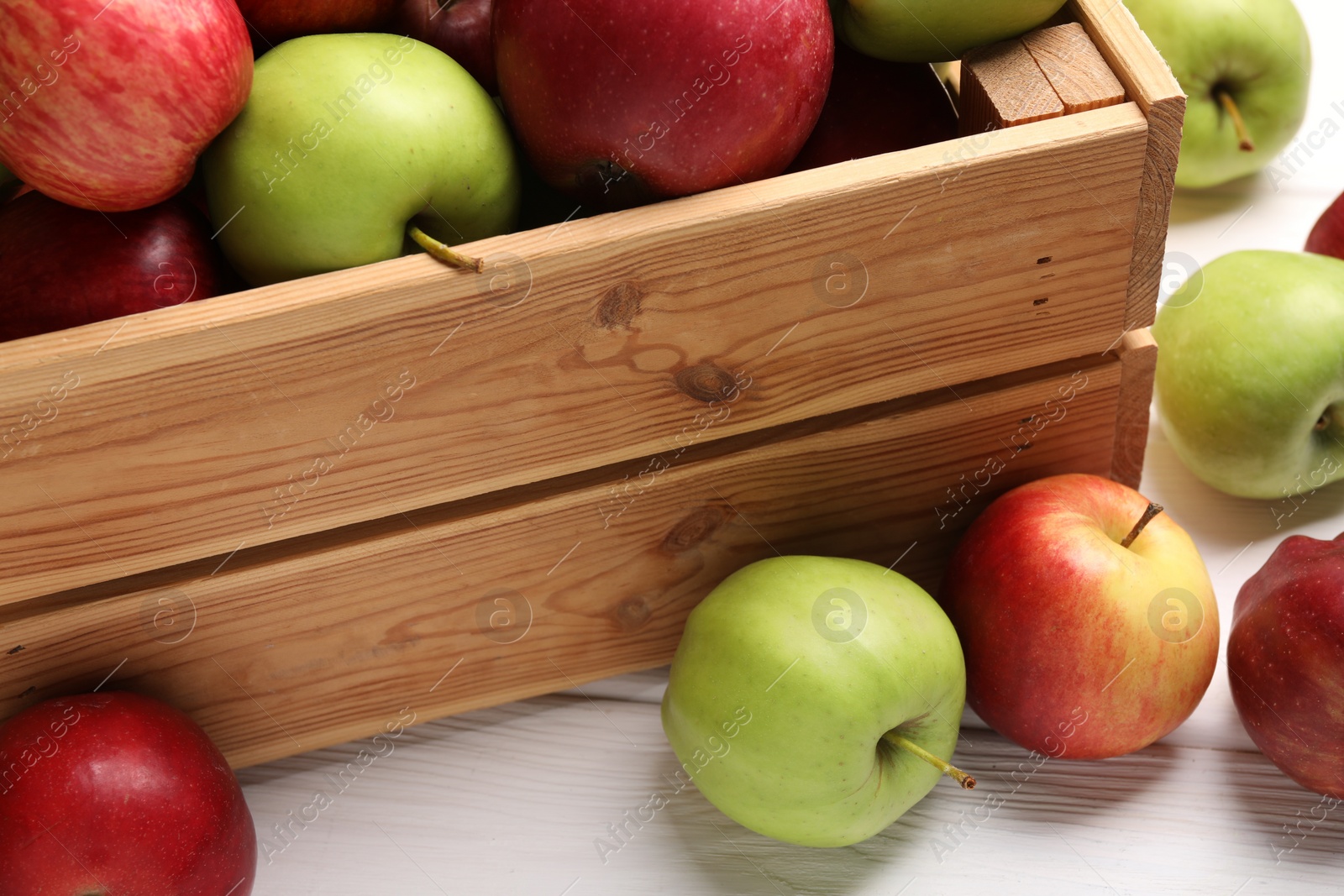 Photo of Crate with ripe red and green apples on white wooden table