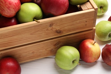 Crate with ripe red and green apples on white wooden table