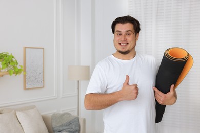 Photo of Overweight man with yoga mat at home, space for text