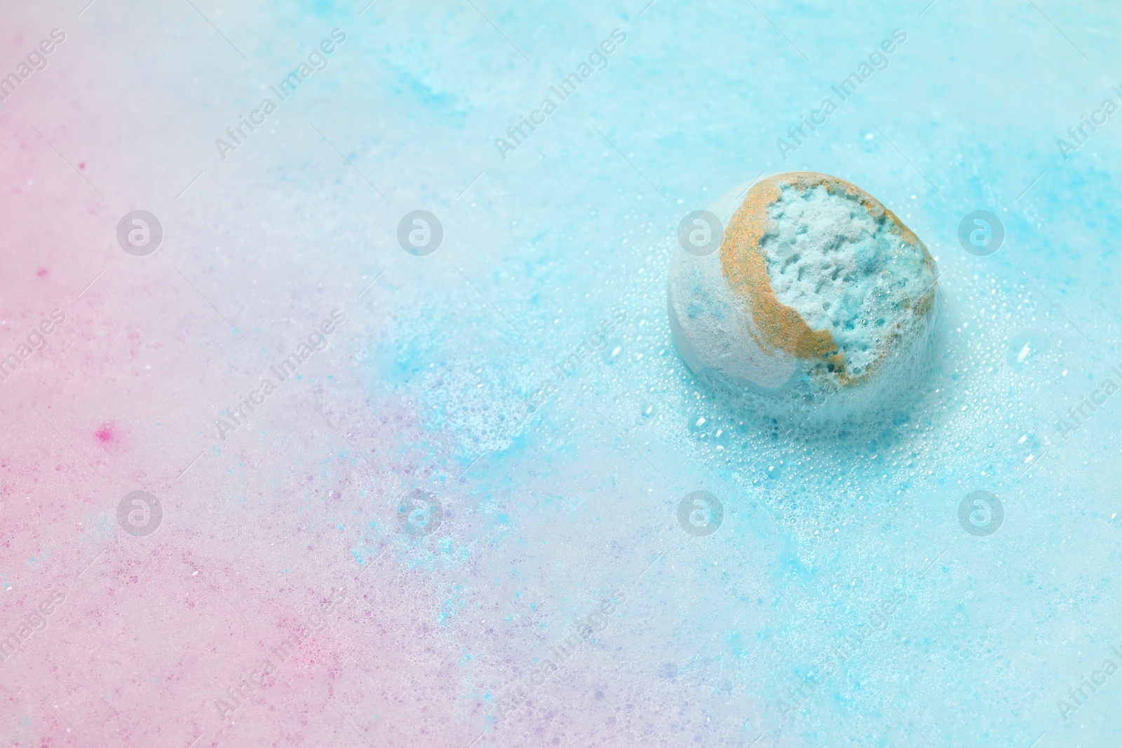 Photo of Light blue bath bomb dissolving in water. Space for text