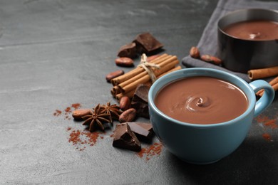 Photo of Yummy hot chocolate in cup on black table. Space for text