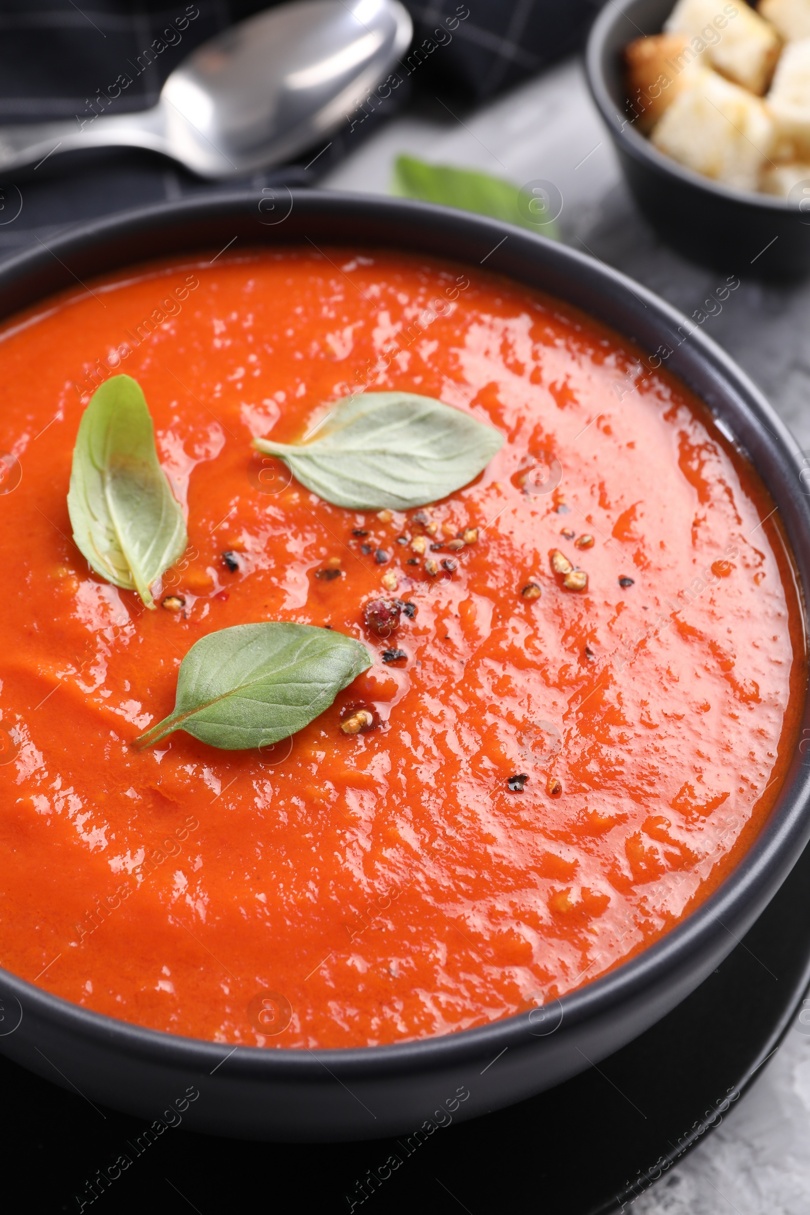 Photo of Delicious tomato cream soup served on grey table, closeup