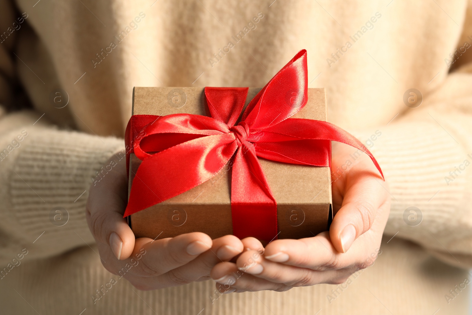 Photo of Woman holding gift box with red bow, closeup