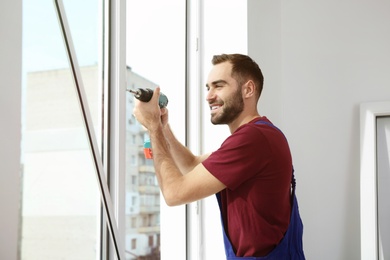 Photo of Construction worker using drill while installing window indoors