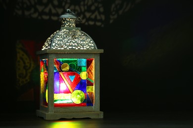 Photo of Decorative Arabic lantern on table against dark background. Space for text