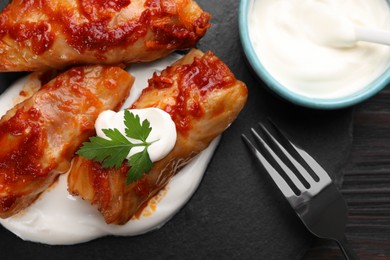 Delicious stuffed cabbage rolls served with sour cream on table, flat lay