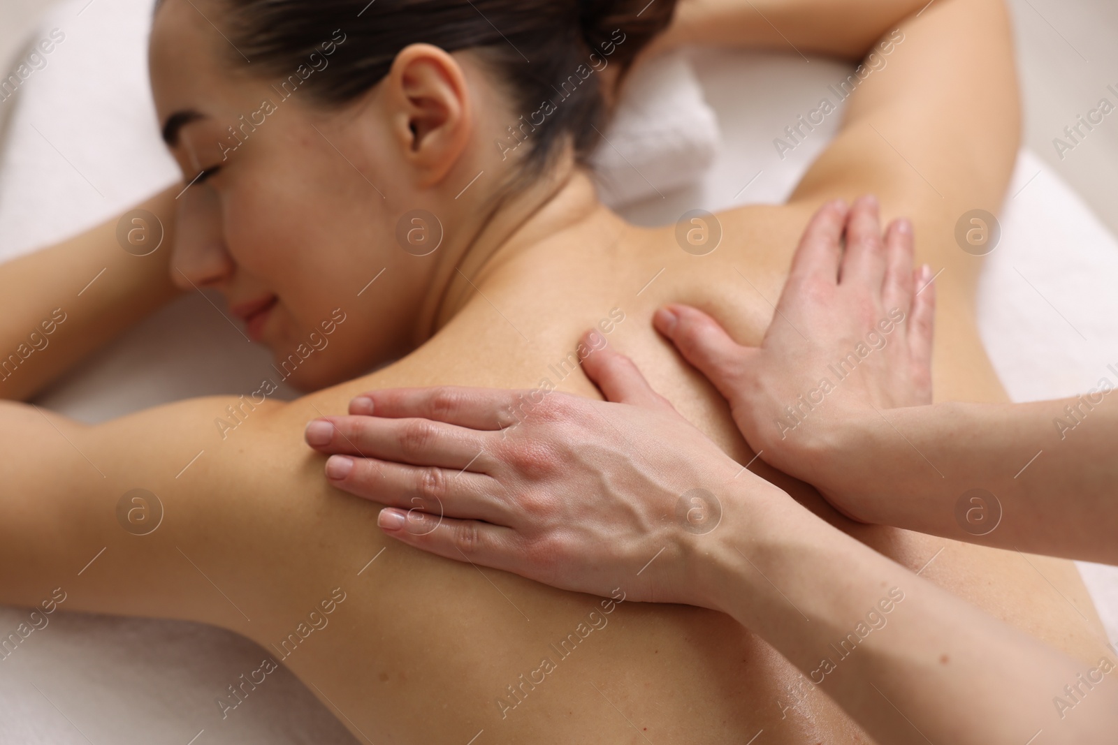 Photo of Woman receiving back massage on couch in spa salon, focus on hands