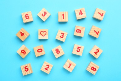 Photo of Wooden cubes with numbers and heart on light blue background, flat lay