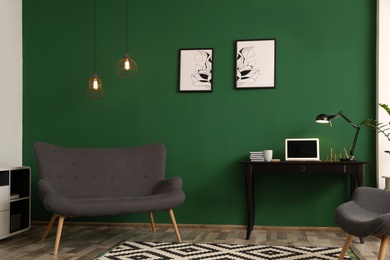 Modern living room interior with workplace near green wall