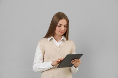 Teenage student using tablet on grey background
