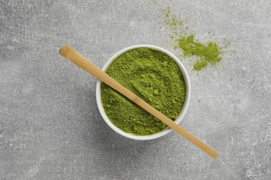 Photo of Green matcha powder and bamboo scoop on light grey table, flat lay