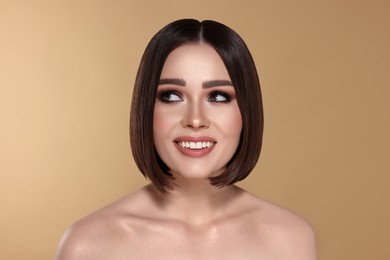 Image of Portrait of pretty young woman with brown hair smiling on beige background