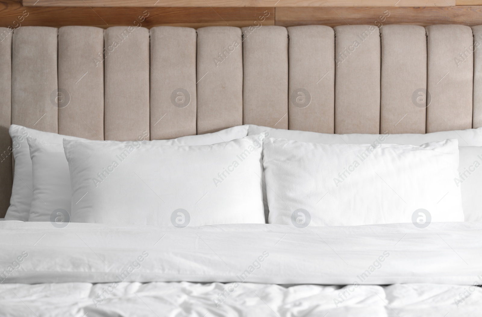 Photo of Bed with soft pillows in room. Modern interior